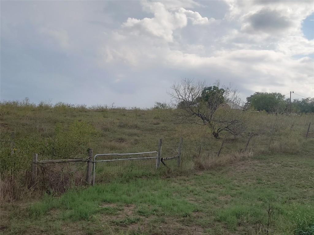 a view of a dry yard with wooden fence