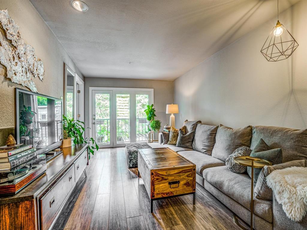 a living room with furniture large window and wooden floor