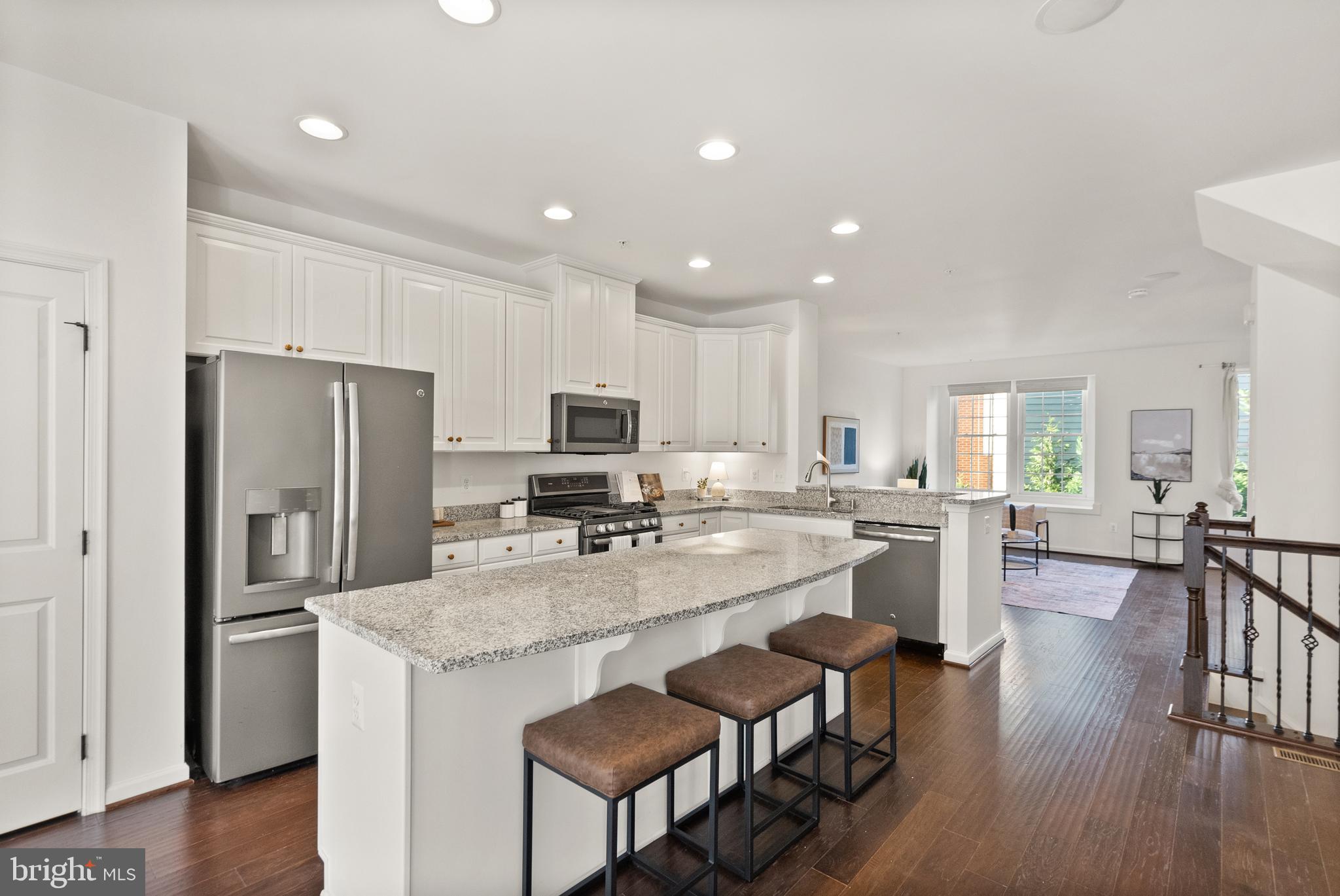 a kitchen with kitchen island granite countertop a center island stainless steel appliances cabinets and wooden floor