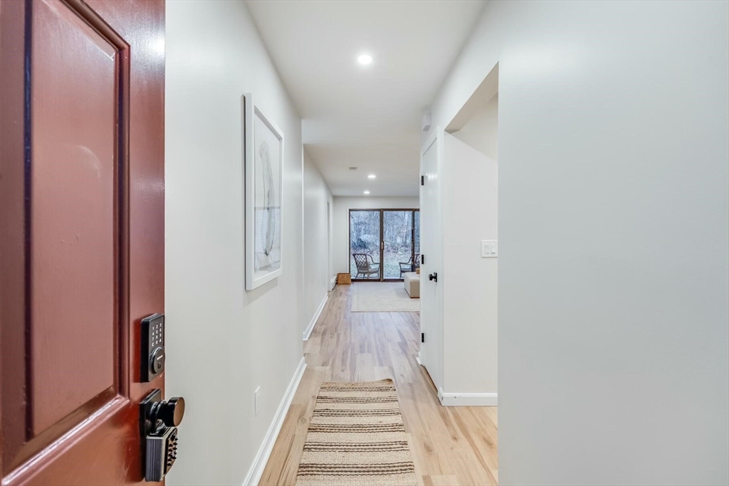 a view of a hallway with wooden floor and a bathroom