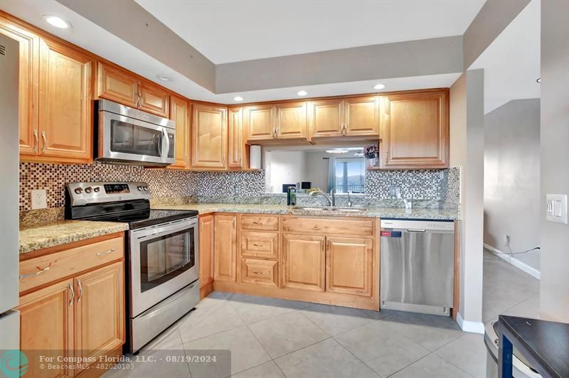 a kitchen with stainless steel appliances granite countertop a stove a sink and a microwave