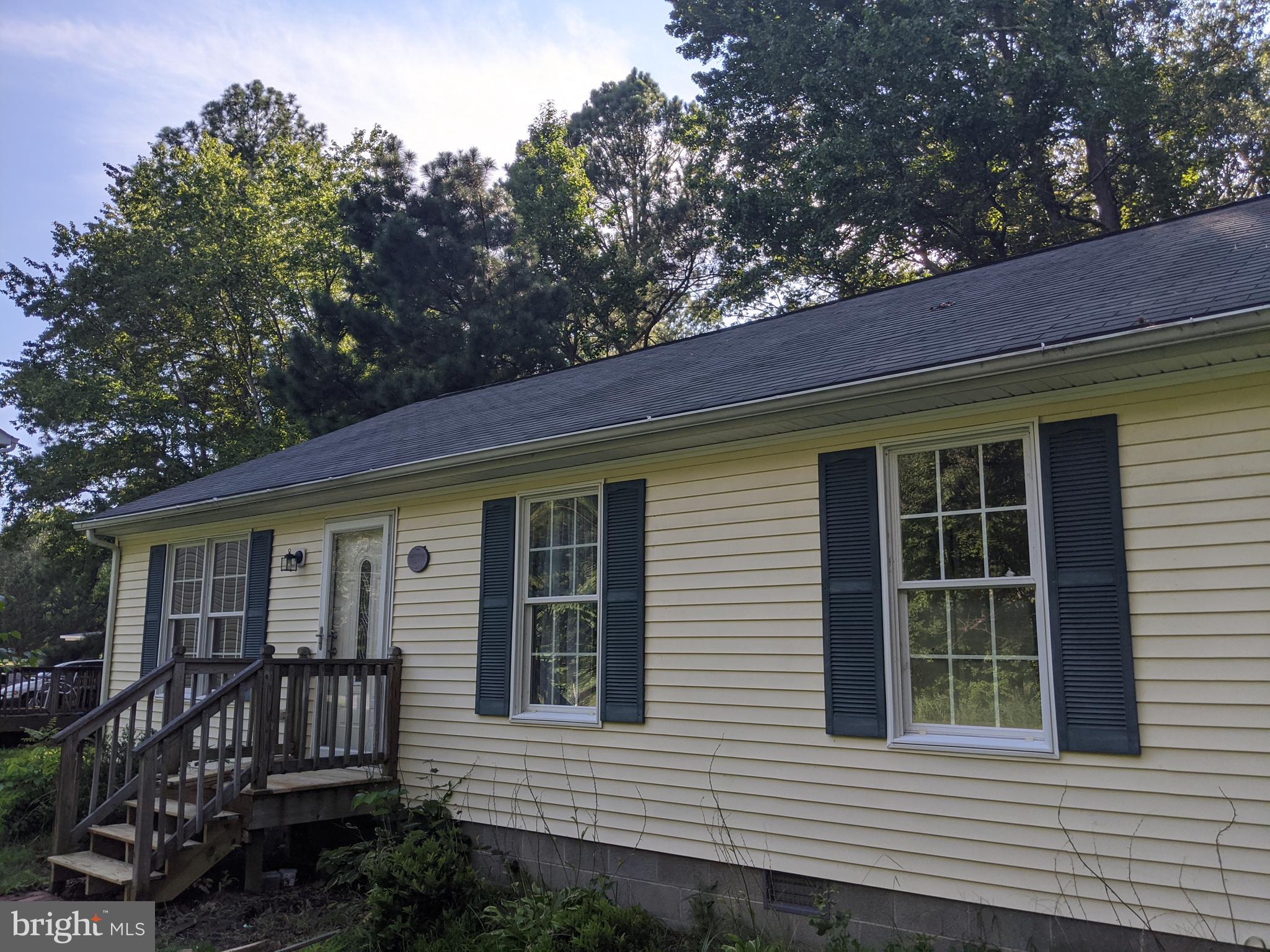 a view of a house with a small deck and a large tree