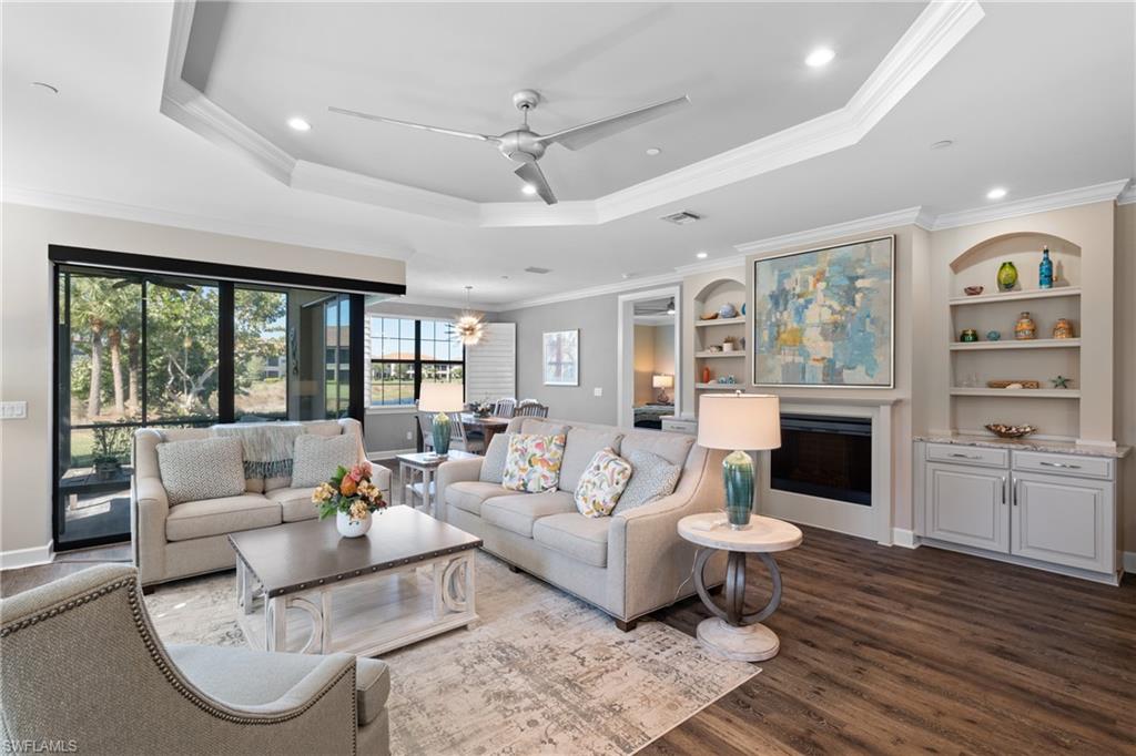 Living room with a tray ceiling, hardwood / wood-style flooring, and ornamental molding