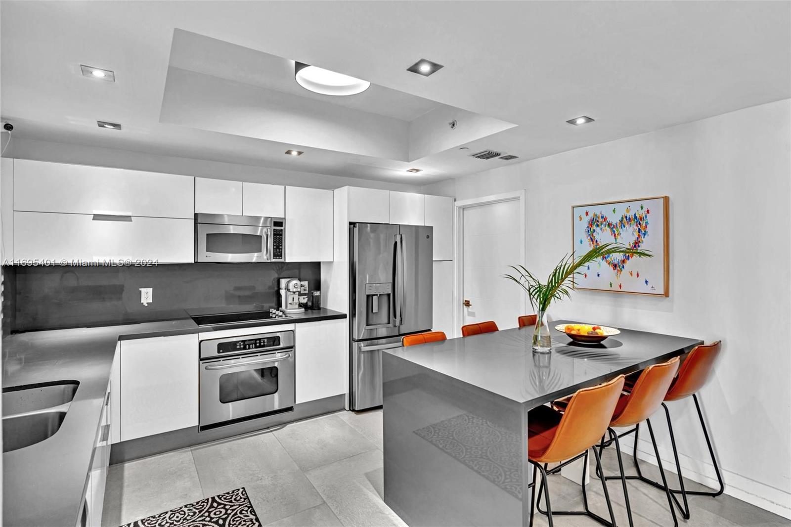 a kitchen that has stainless steel appliances a stove a refrigerator and a dining table