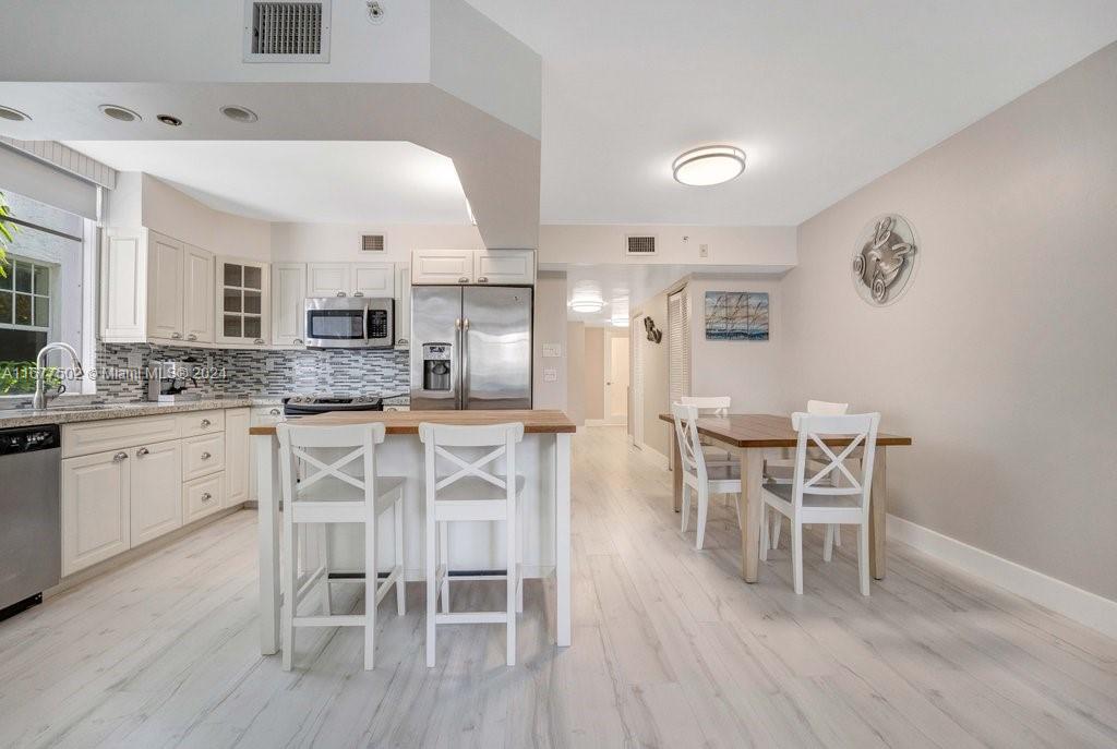 a kitchen with stainless steel appliances kitchen island granite countertop a table and chairs in it