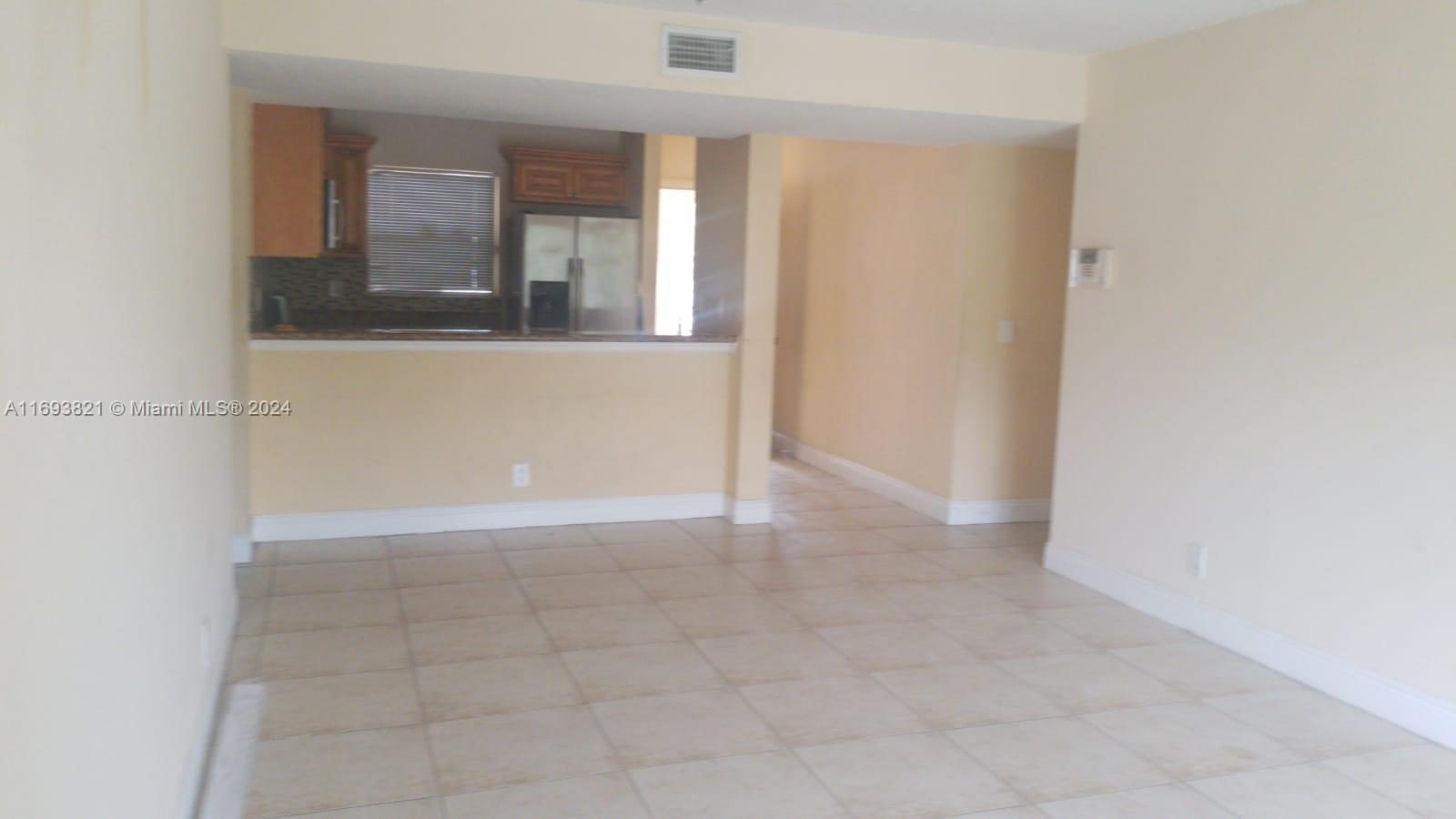 a view of an empty room with mirror and a window