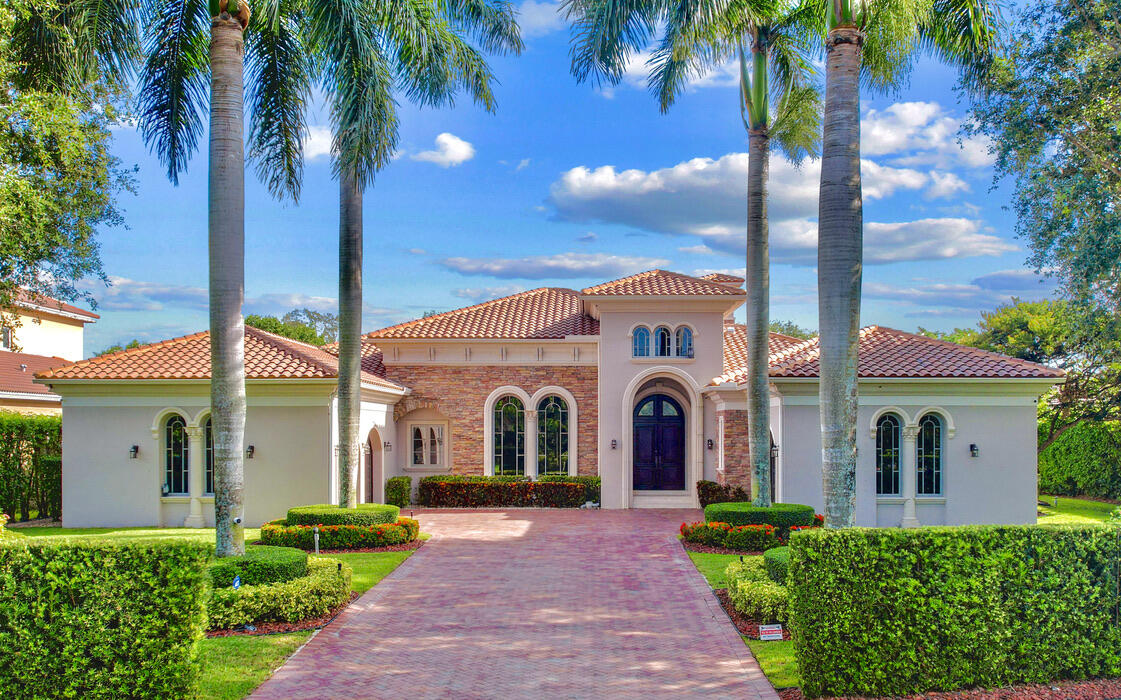 a view of a white house with a yard and palm trees