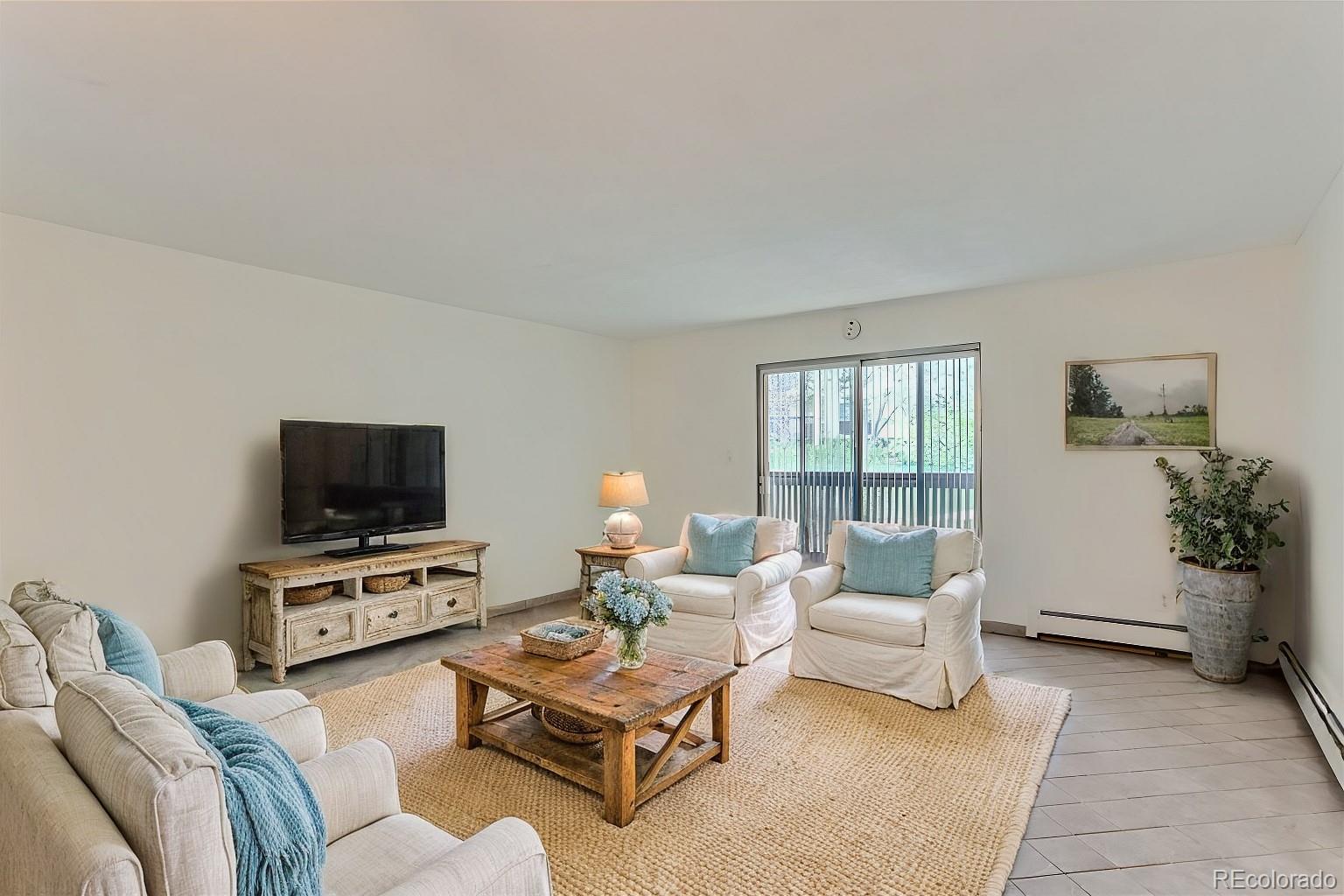 a living room with furniture a flat screen tv and a window