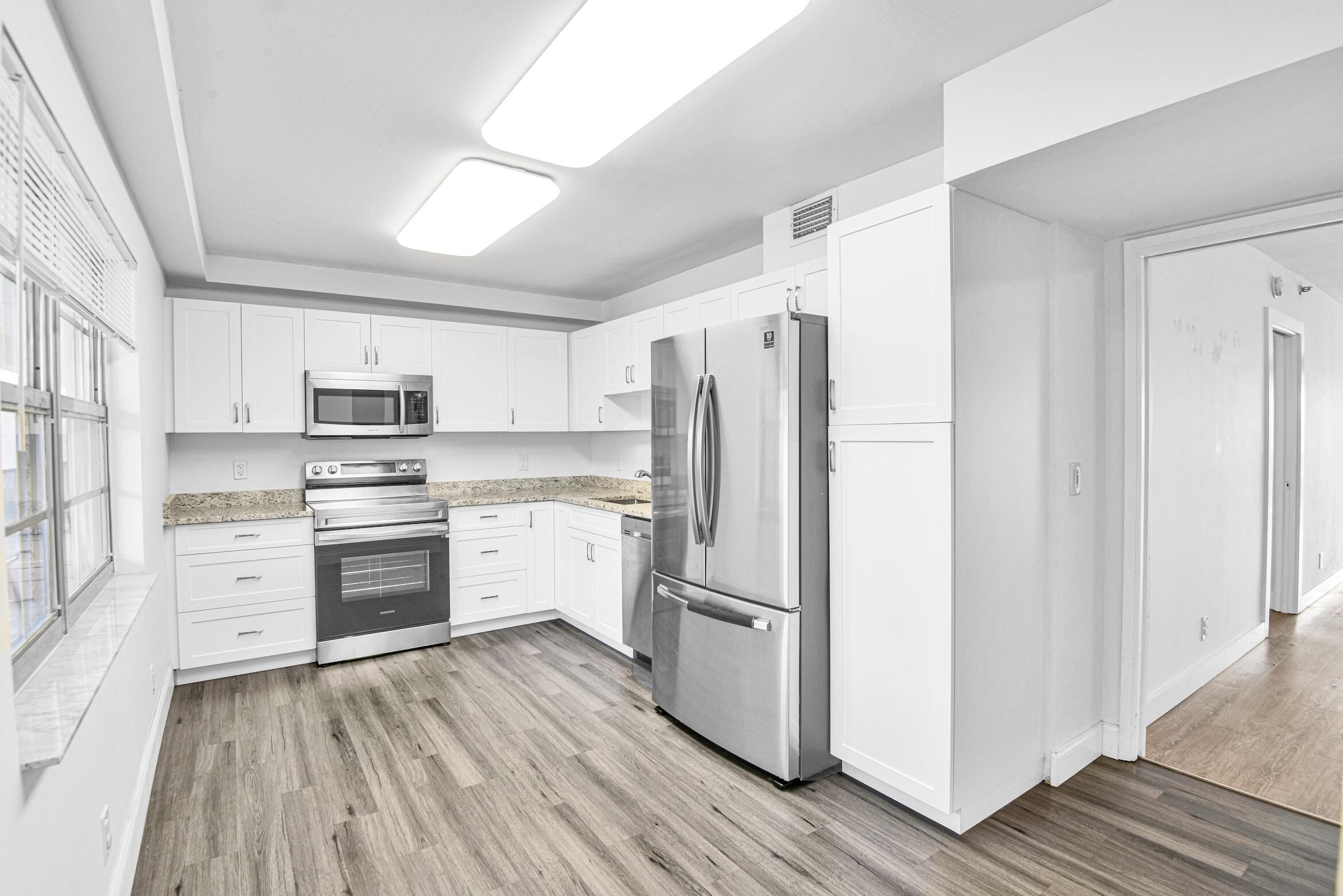 a kitchen with a refrigerator a stove top oven and cabinets