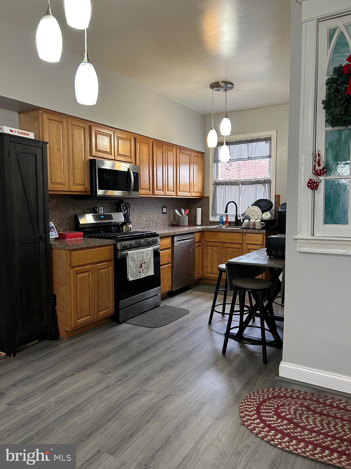 a kitchen with stainless steel appliances granite countertop a sink dishwasher a stove a refrigerator a microwave oven with cabinets and wooden floor