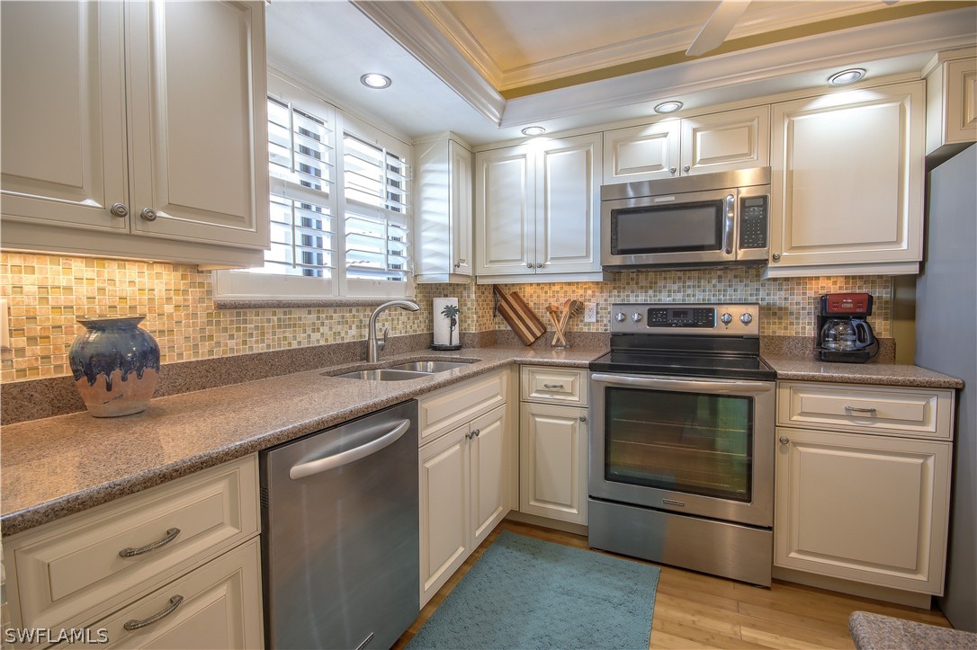 a kitchen with granite countertop white cabinets stainless steel appliances and a sink