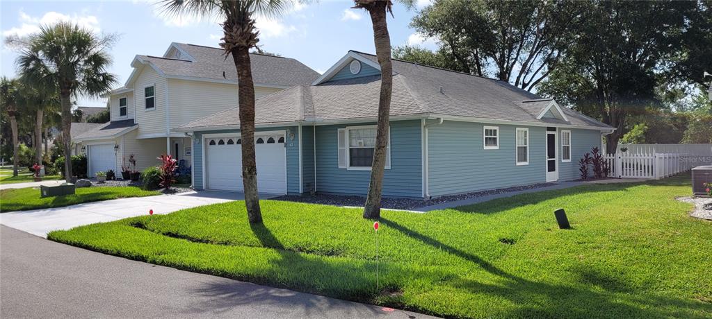 a view of a white house with a yard and palm trees