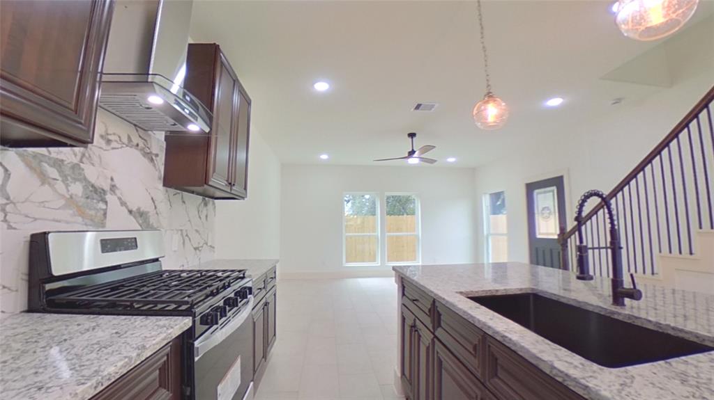 a kitchen with stainless steel appliances granite countertop a sink a stove and a wooden cabinets