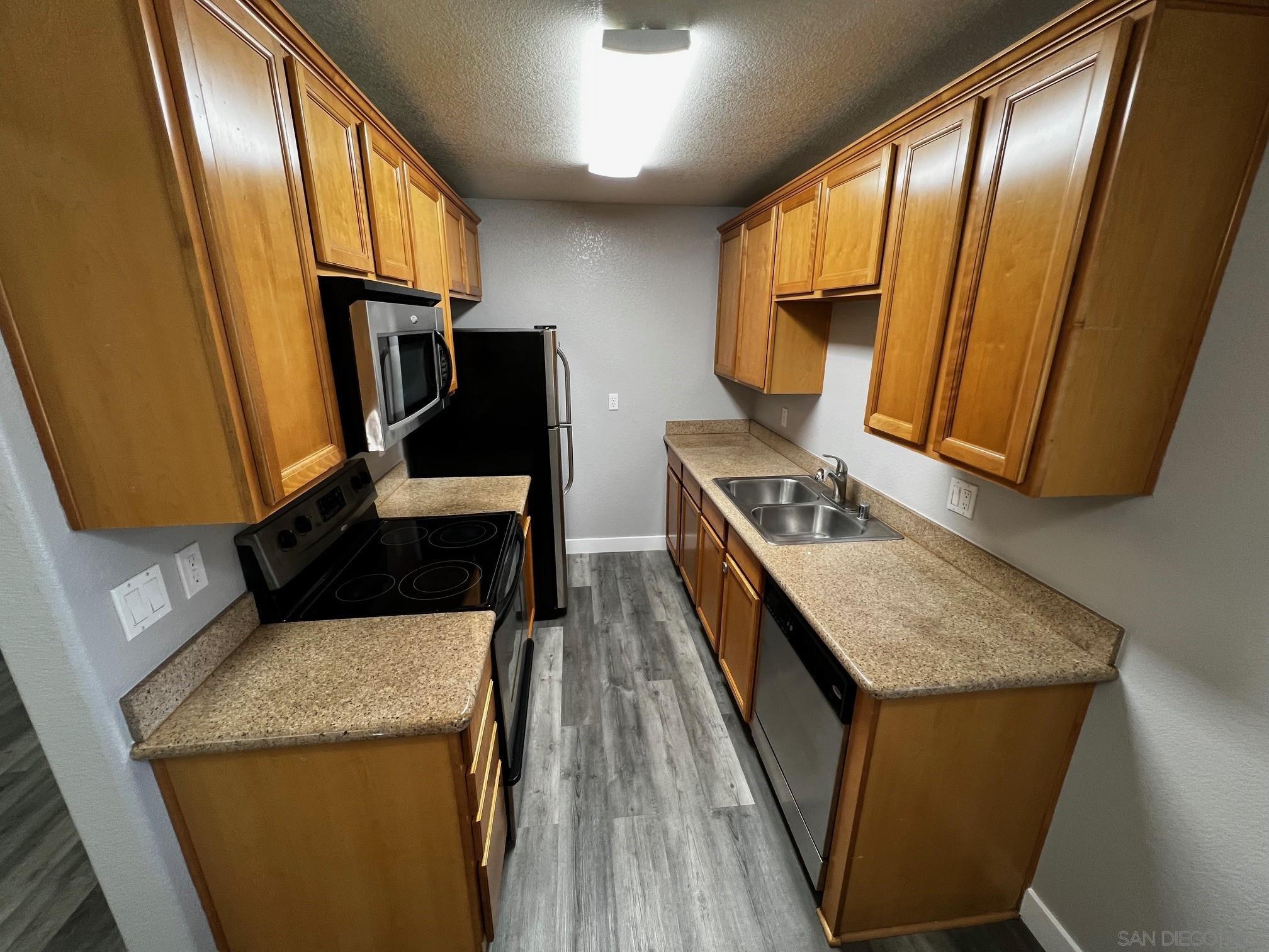 a kitchen with a sink a refrigerator and wooden floor