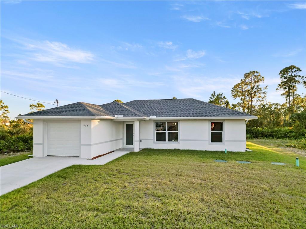 Ranch-style home featuring a garage and a front lawn