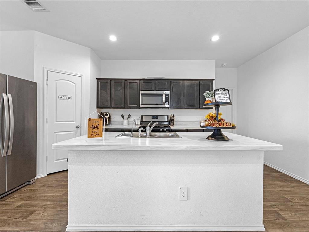 a kitchen with stainless steel appliances a sink a stove a refrigerator cabinets and a counter top space