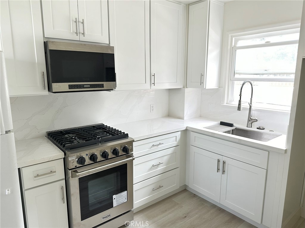 a kitchen with white cabinets and appliances