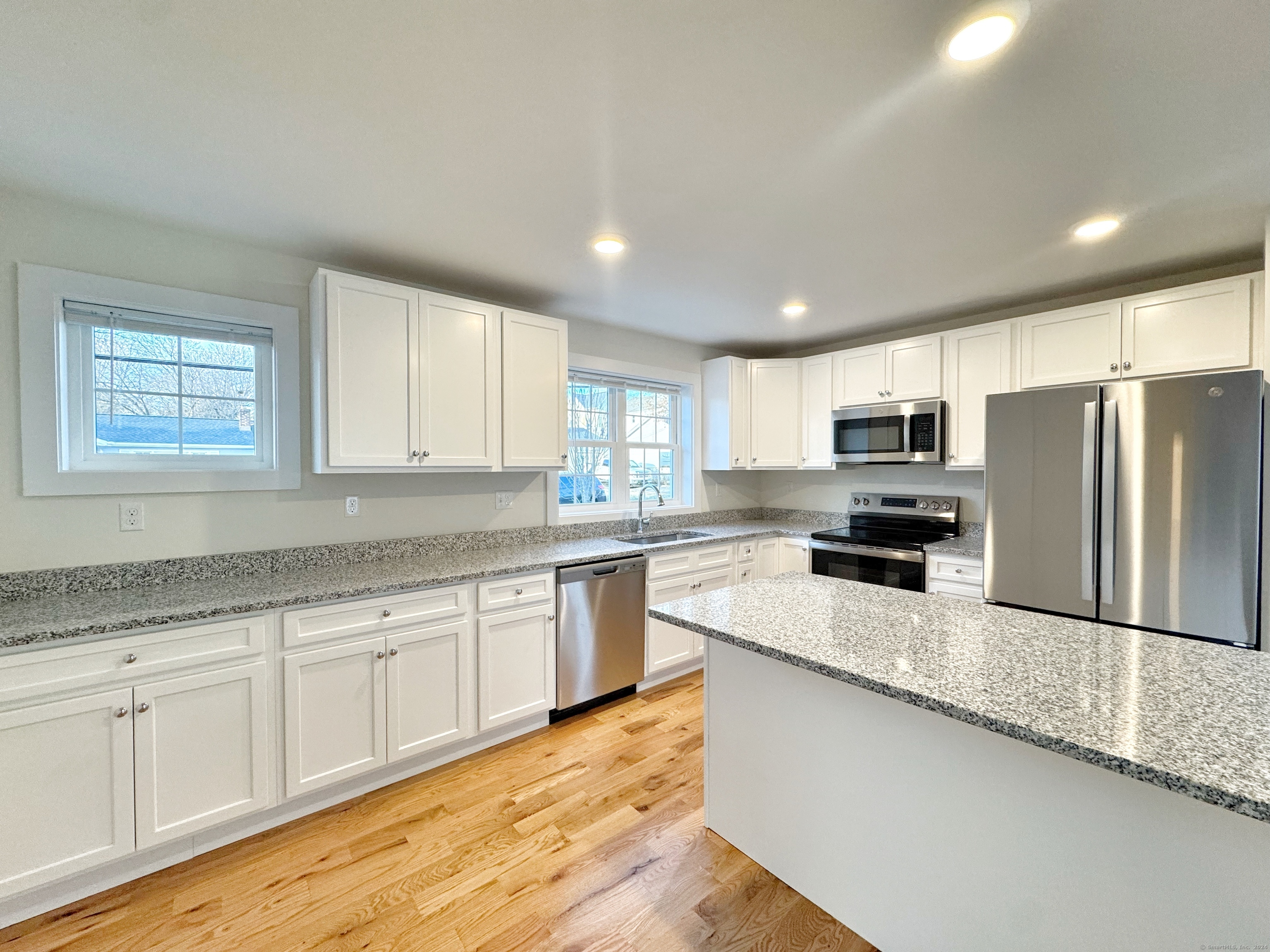 a kitchen with stainless steel appliances granite countertop a sink refrigerator and microwave