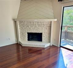 an empty room with wooden floor fireplace and windows