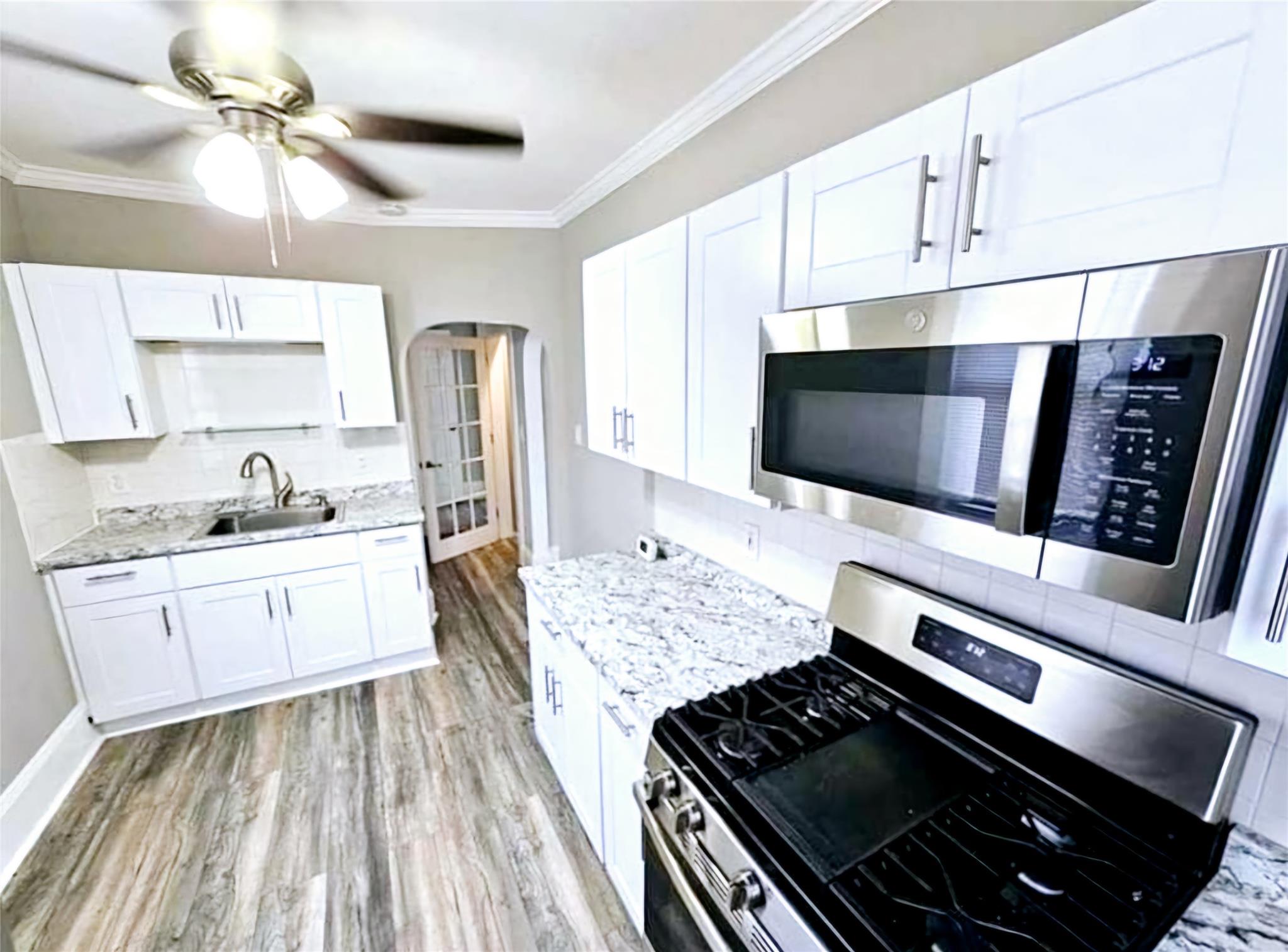 Kitchen with crown molding, sink, white cabinets, and appliances with stainless steel finishes