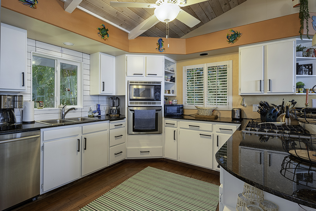 a kitchen with stainless steel appliances white cabinets a sink a stove a microwave and wooden floors