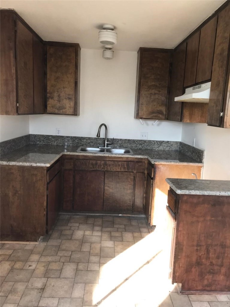 a kitchen with granite countertop a sink a stove and cabinets