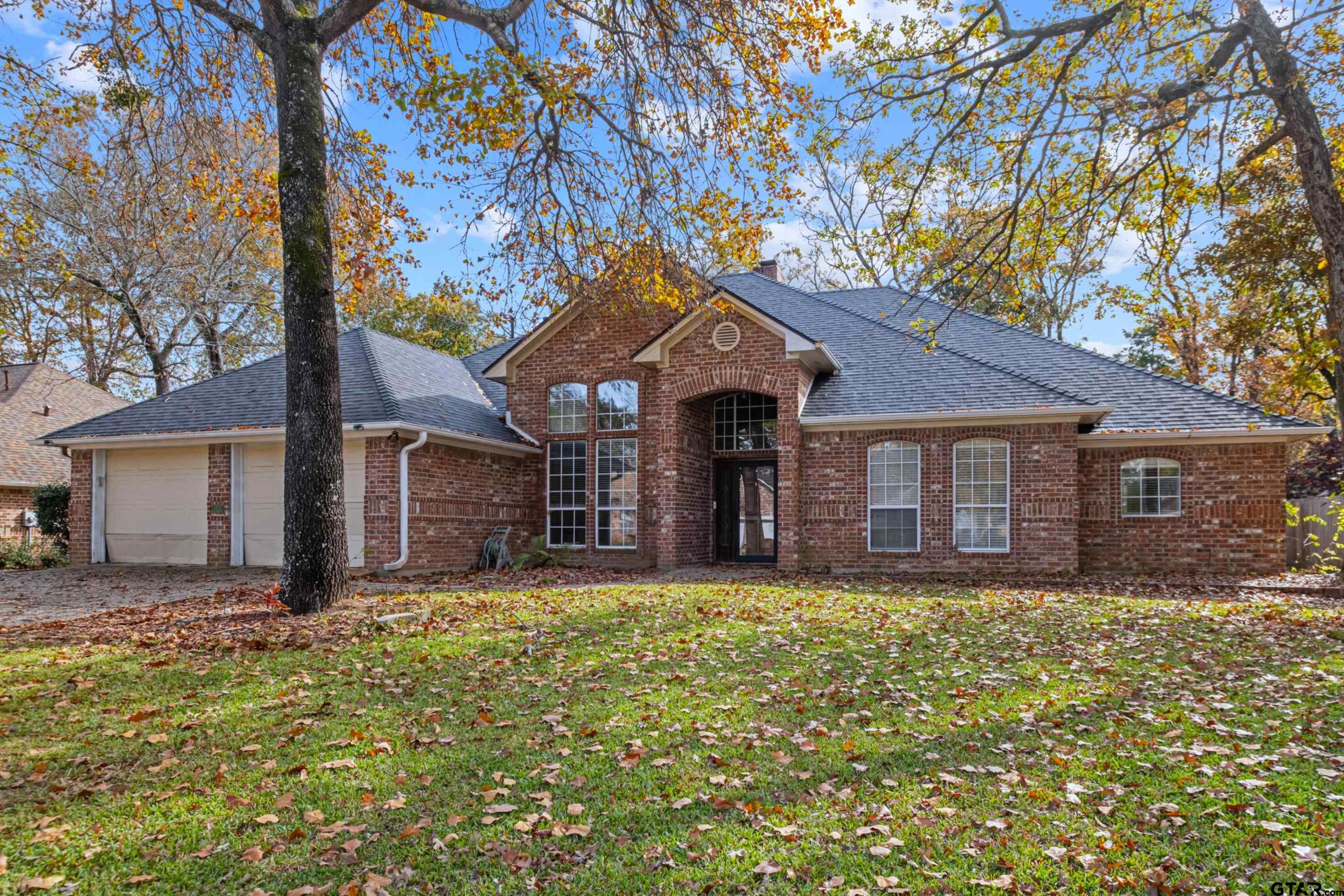 a front view of house with yard and trees in the background