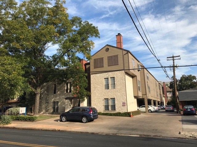 a front view of a building with lot of cars and trees