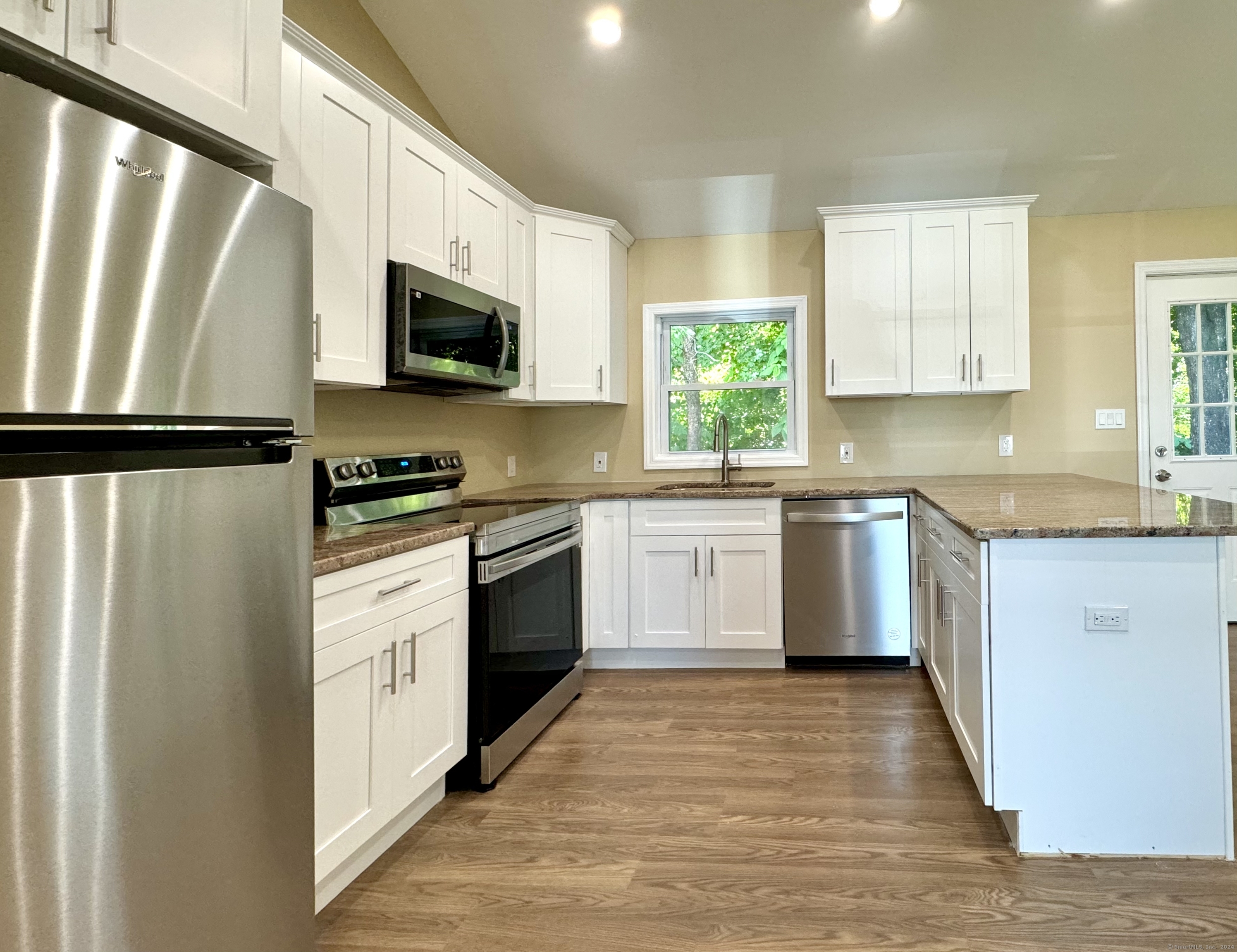 a kitchen with white cabinets stainless steel appliances a sink and a window