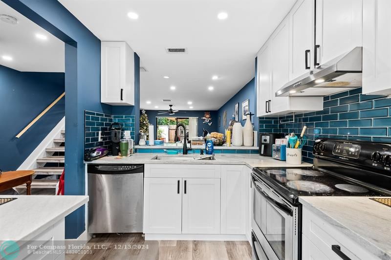 a kitchen with kitchen island a stove a sink a refrigerator and chairs