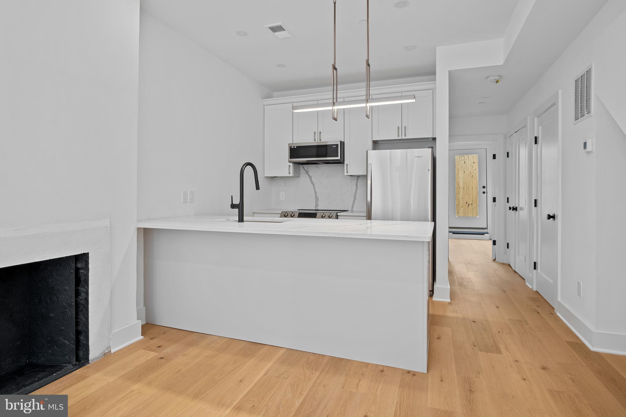 a kitchen with stainless steel appliances a refrigerator and a wooden floor