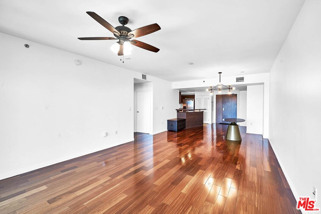 a view of empty room with wooden floor and ceiling fan