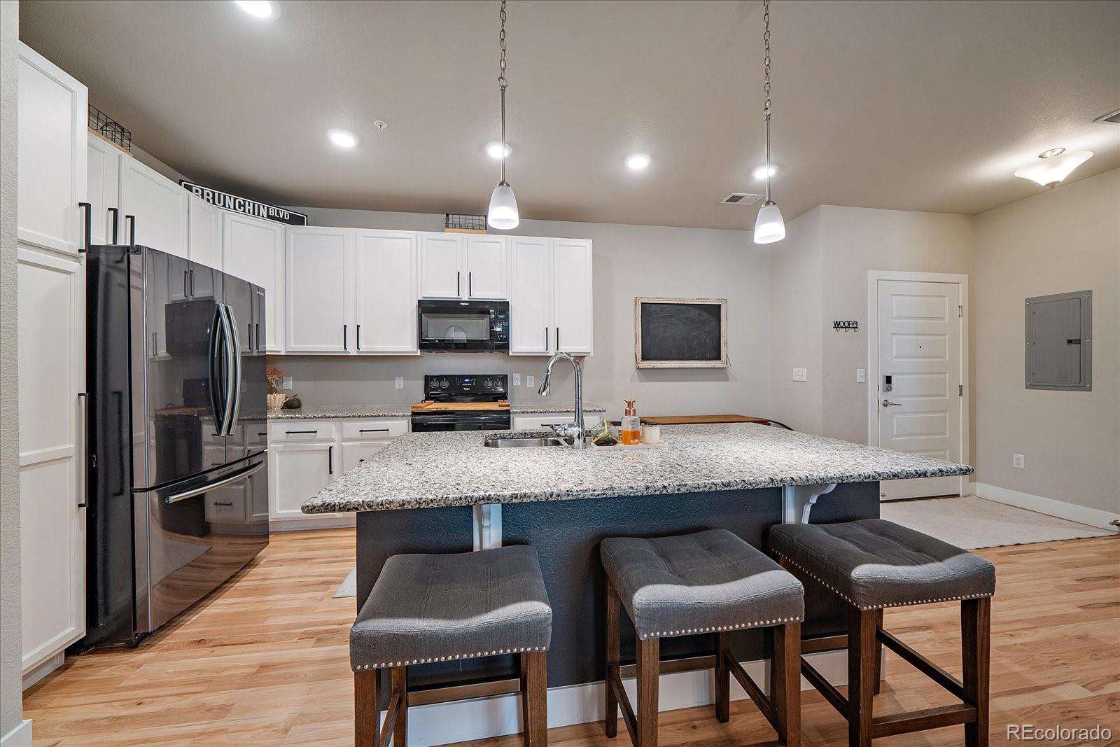 a kitchen with stainless steel appliances granite countertop a table chairs refrigerator and sink