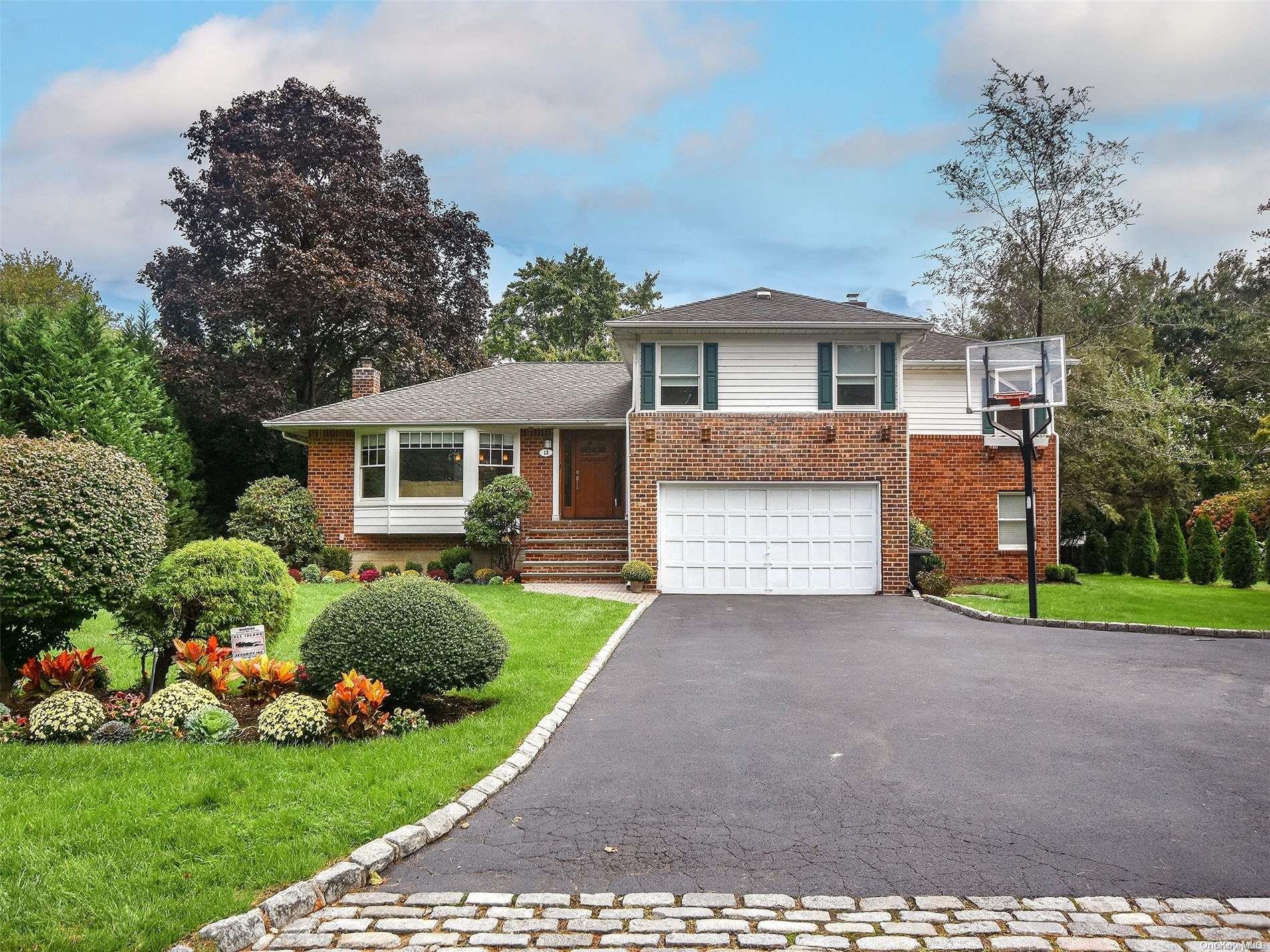 a front view of a house with a garden and trees