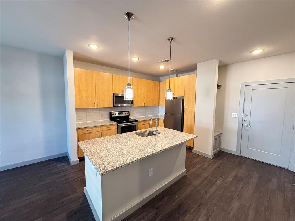 a large kitchen with a center island wooden floor stainless steel appliances and windows