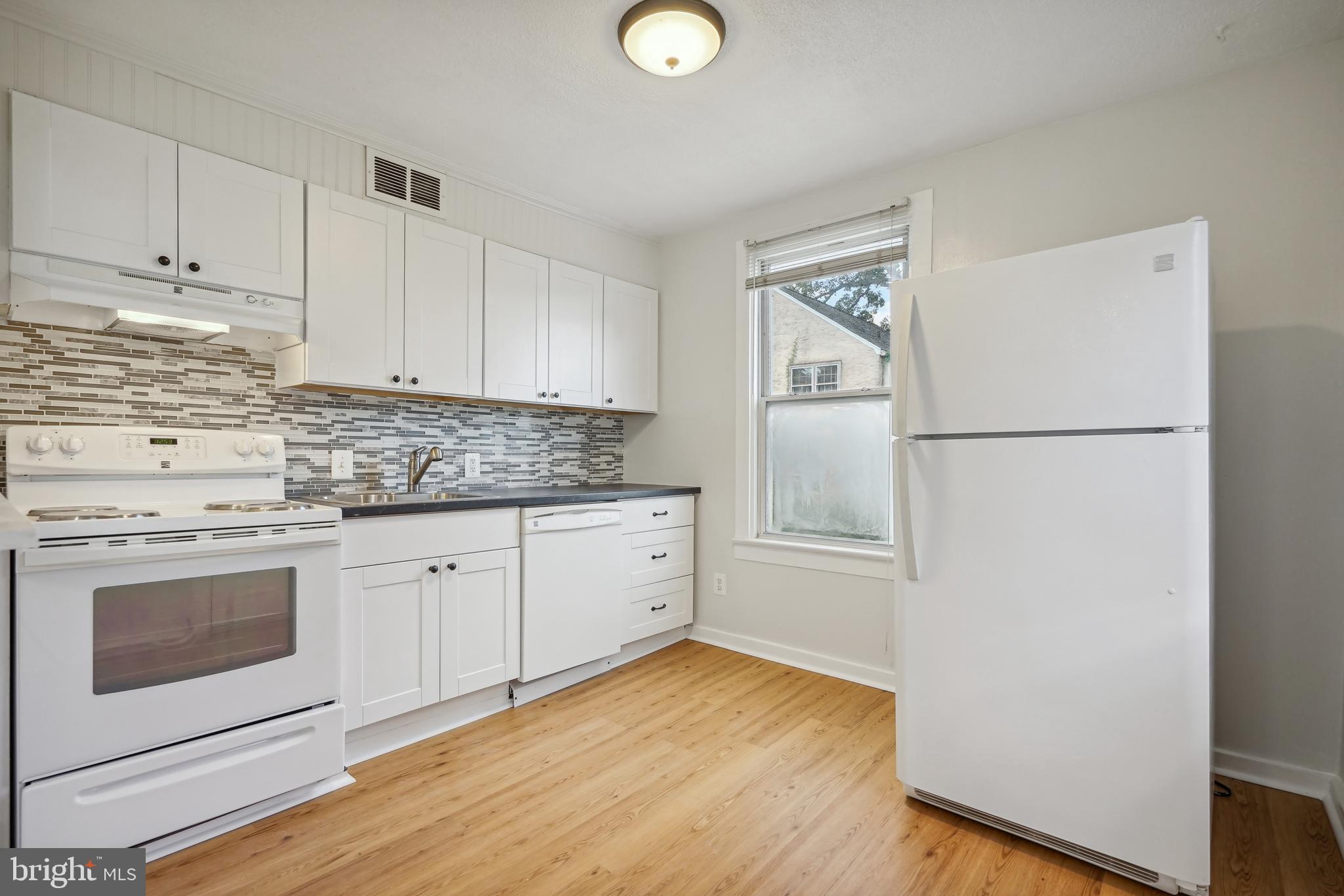 a kitchen with granite countertop white cabinets and white appliances