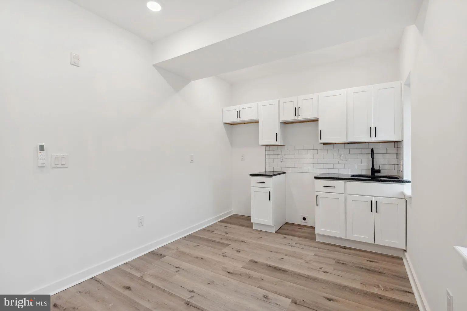 a kitchen with granite countertop white cabinets and wooden floor