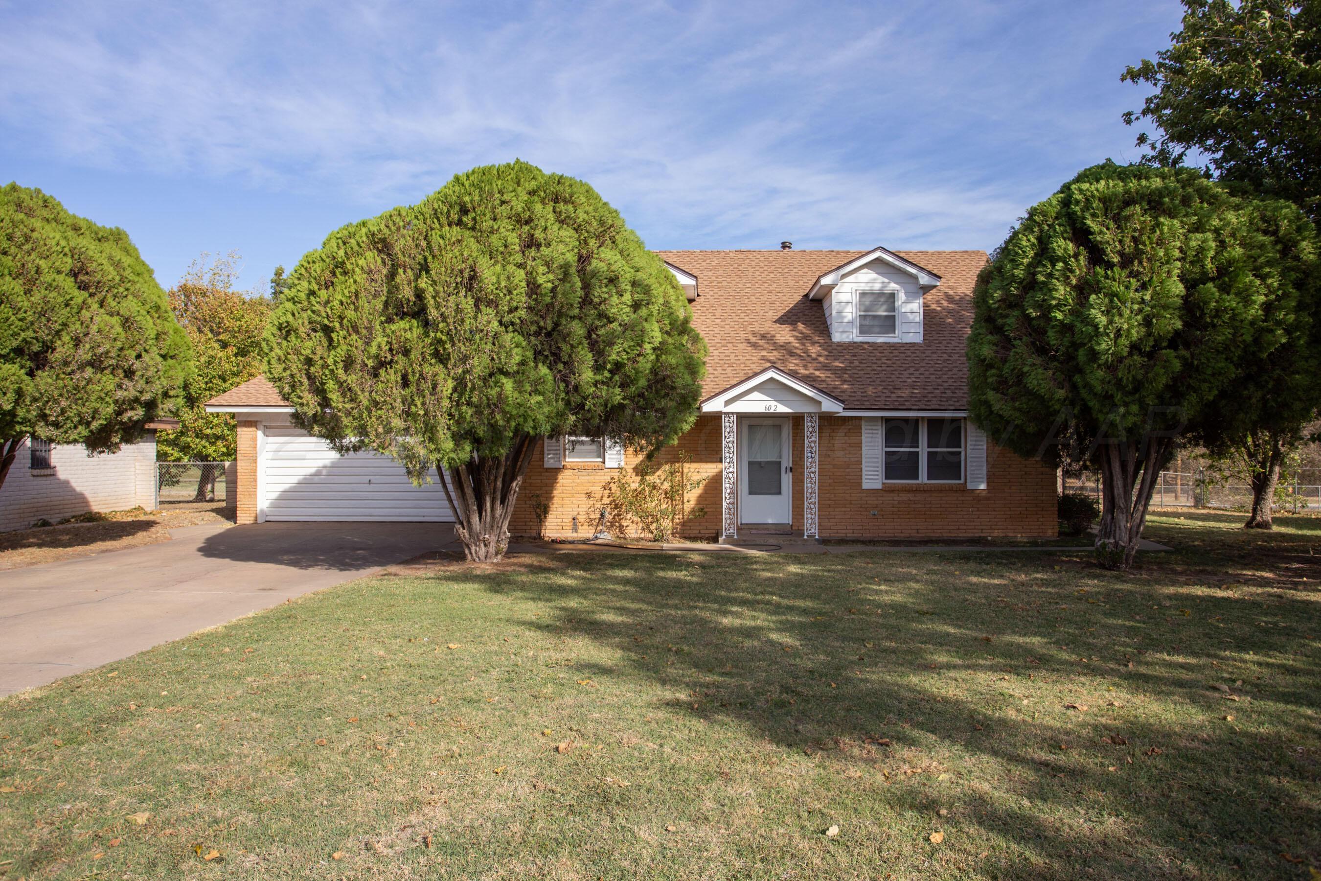 a front view of a house with a garden and tree