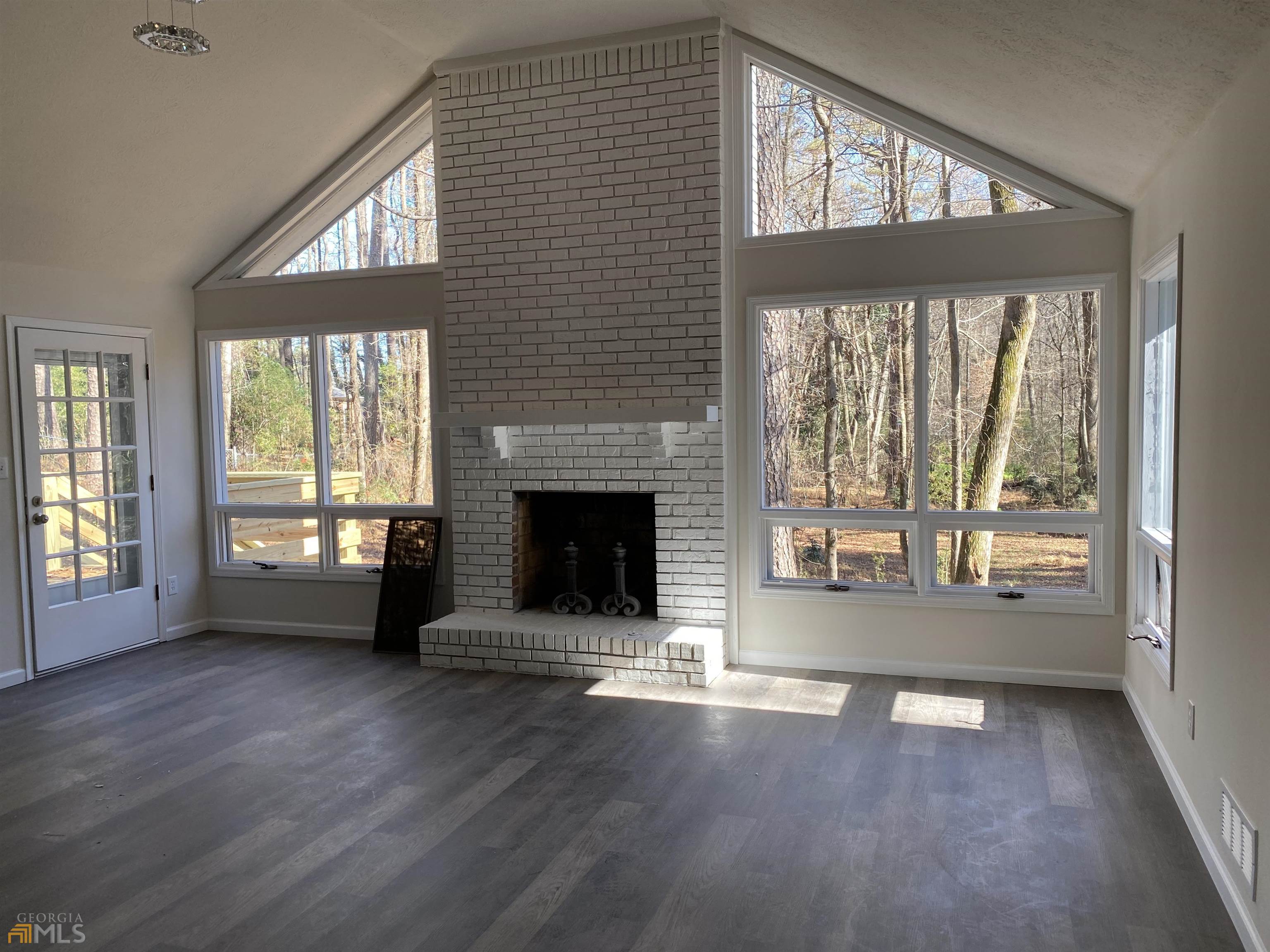 an empty room with wooden floor fireplace and windows