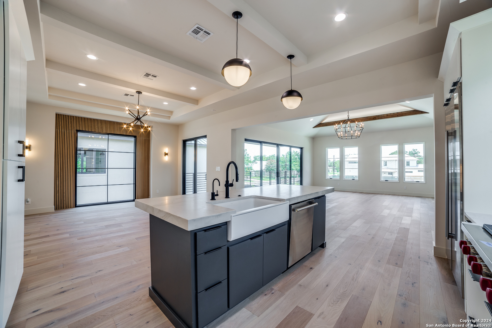 a large white kitchen with a large island oven a stove white cabinetry and wooden floor