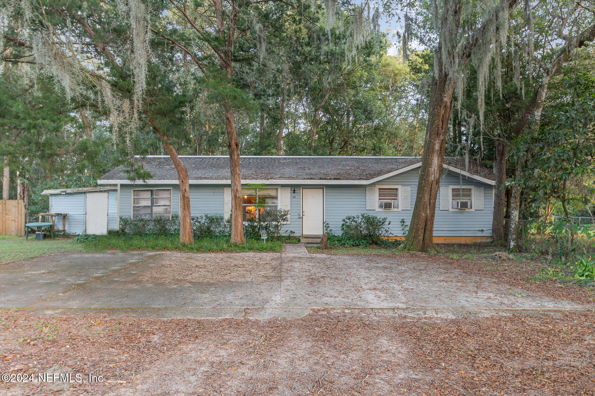 a view of a house with a yard and large trees