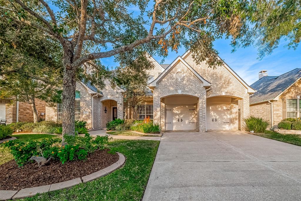 This charming brick home features a welcoming 3 car tandem garage, manicured landscaping, and a shaded front yard, providing a perfect blend of style and comfort.