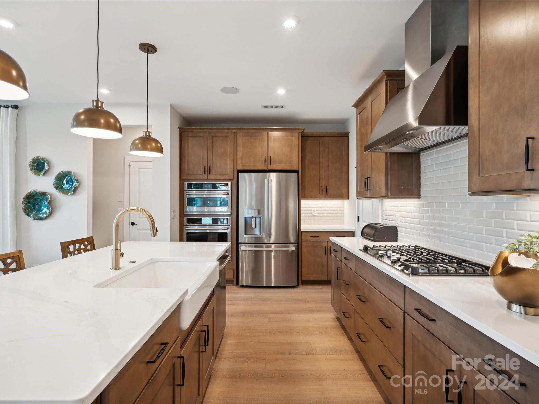 a kitchen with stainless steel appliances granite countertop a sink a stove and refrigerator