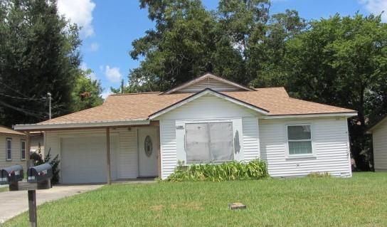 a view of a yard in front of a house with plants and large tree