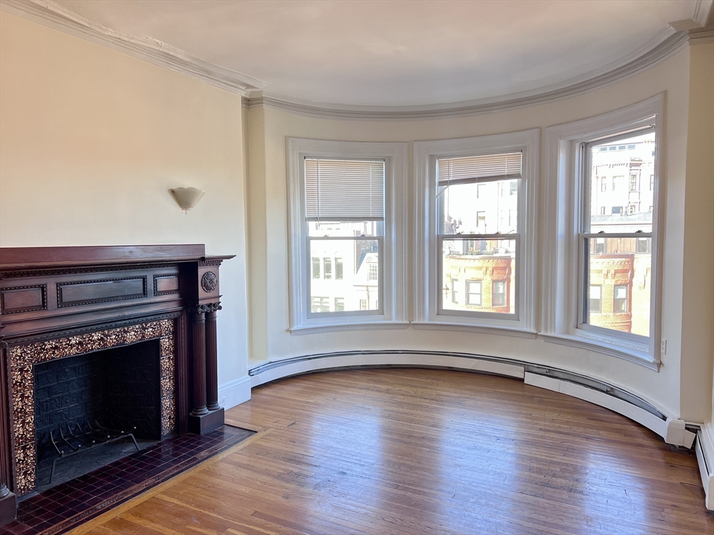 a living room with wooden floor and a fireplace