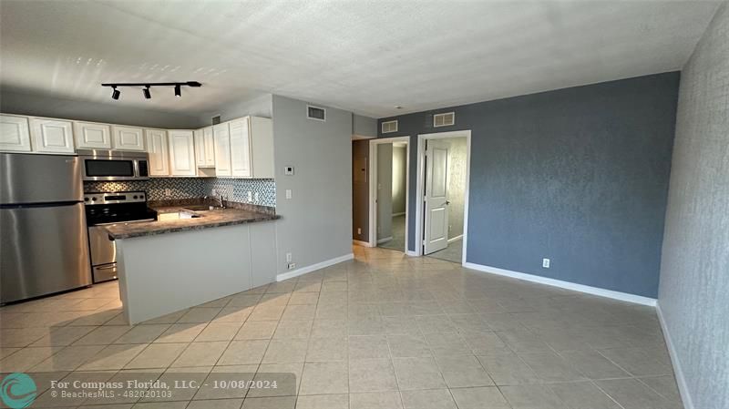 a kitchen with a refrigerator a stove top oven and white cabinets