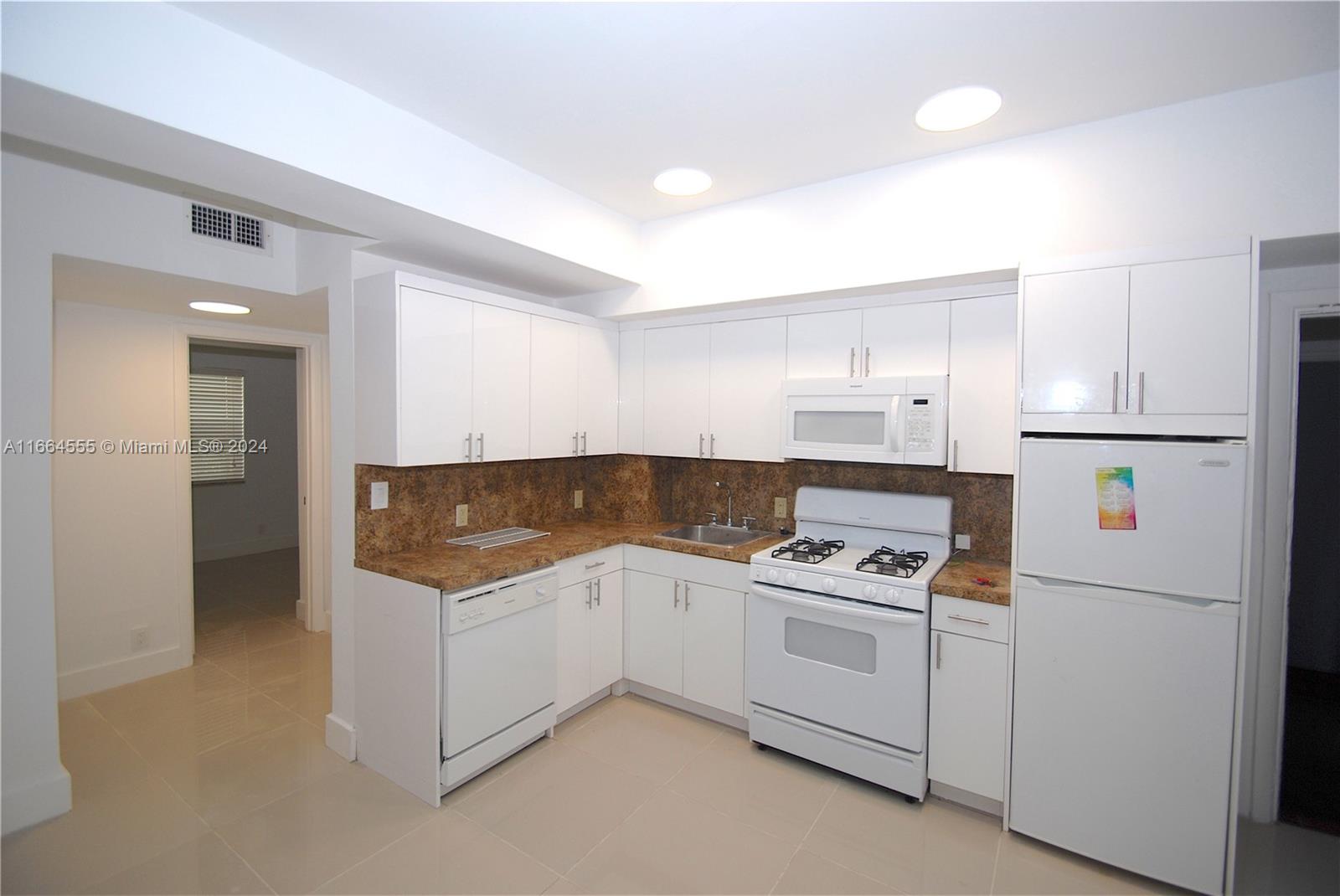 a kitchen with white cabinets and white appliances