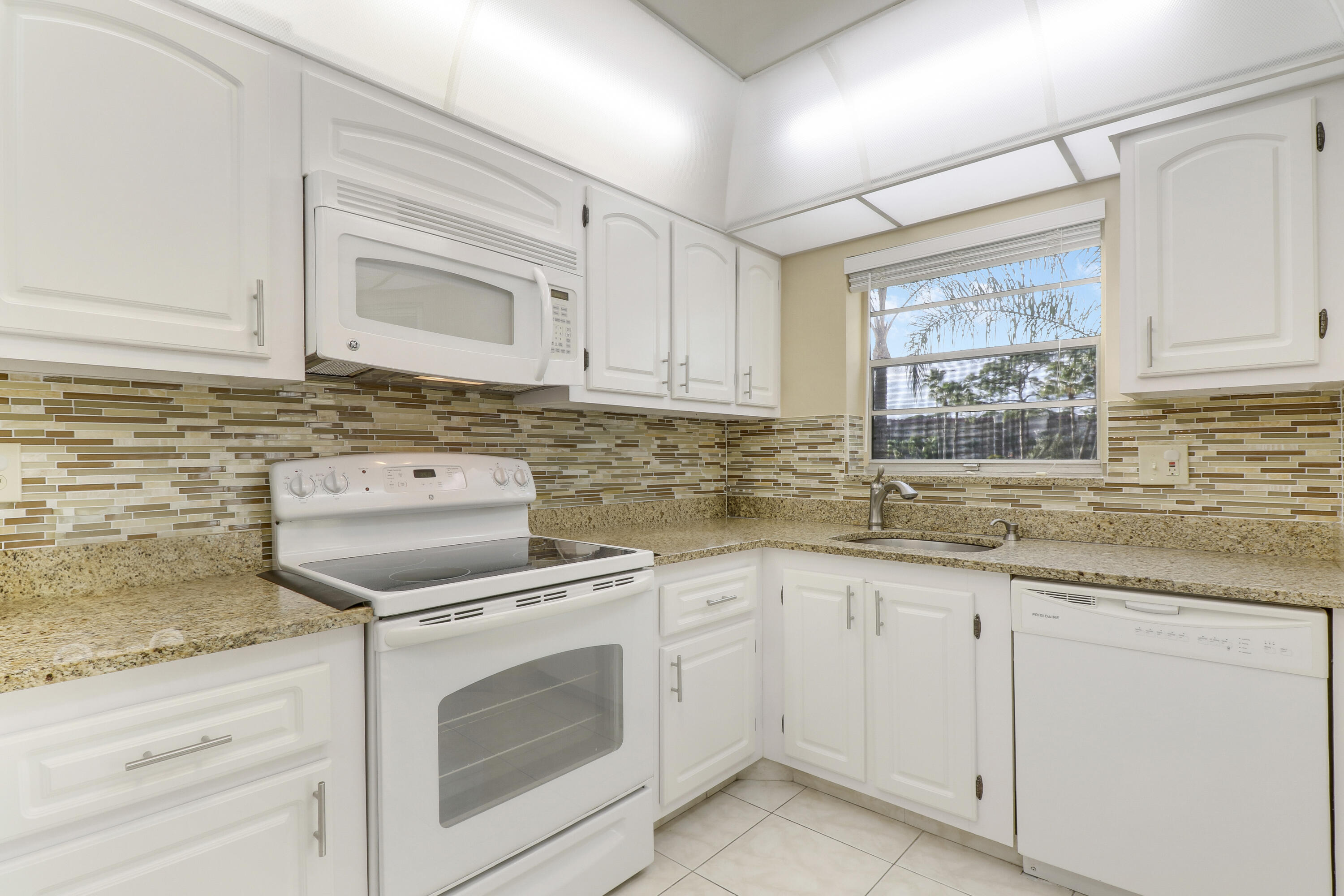 a kitchen with granite countertop white cabinets and white appliances