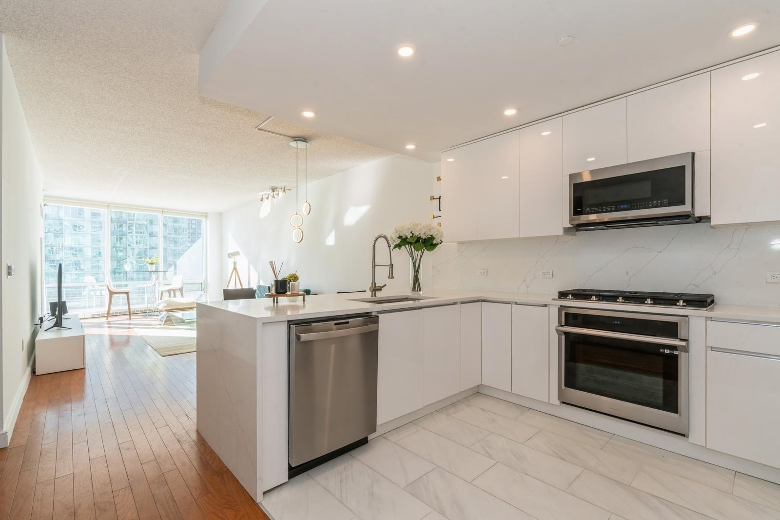 a kitchen with stainless steel appliances kitchen island granite countertop a stove top oven a sink dishwasher and a microwave oven with wooden floor