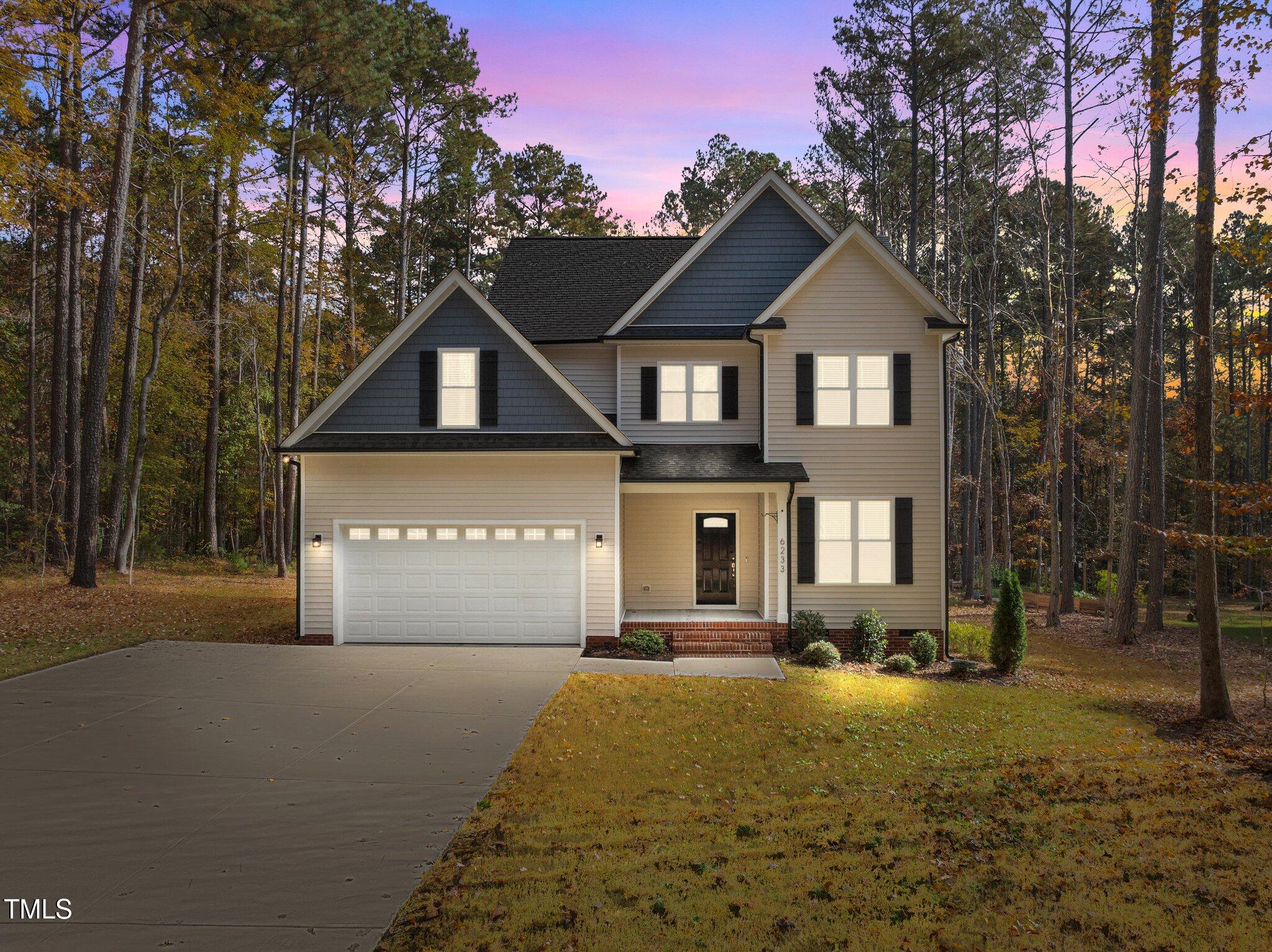 a front view of a house with yard and parking